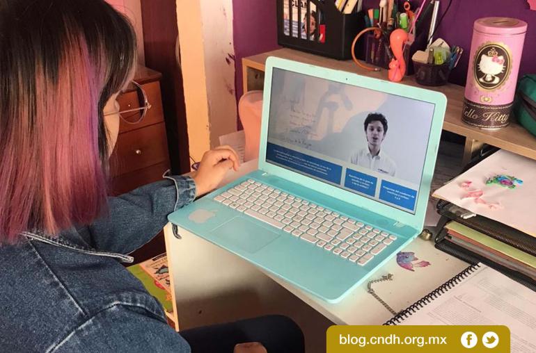 Niña de espaldas tomando clases en una laptop.